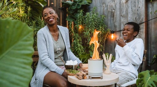 Mother and son laughing around table top fire pit