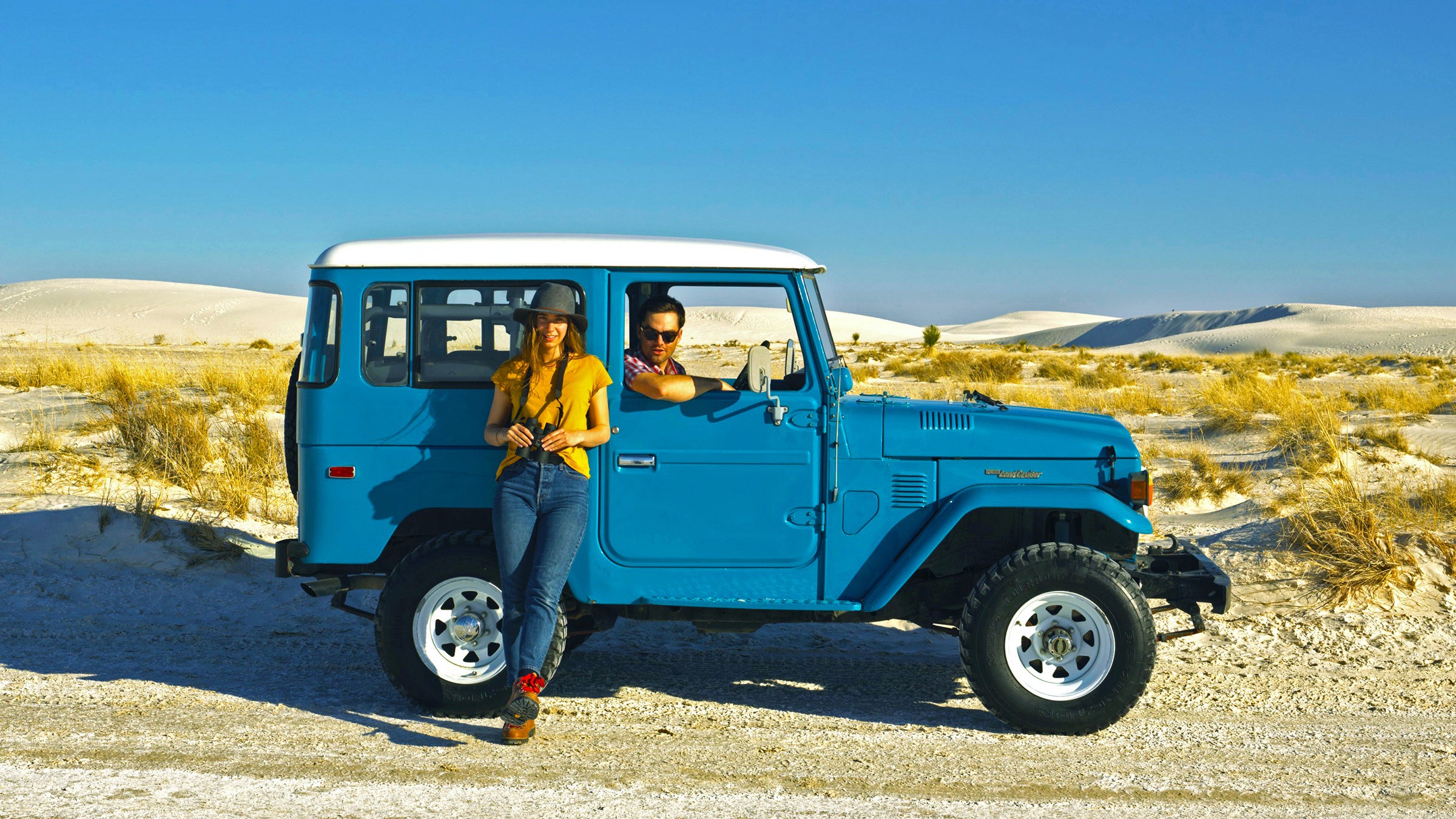 Two travelers with a land cruiser in the desert