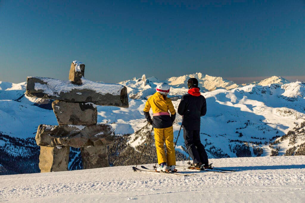 Skiers admiring the Inukshuk in Whistler Blackcomb.