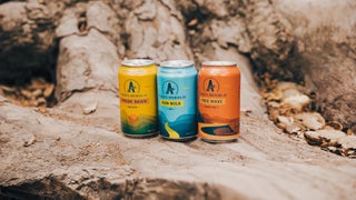 Three Athletic Brewing Company non-alcoholic beers on a log