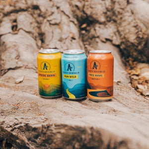 Three Athletic Brewing Company non-alcoholic beers on a log