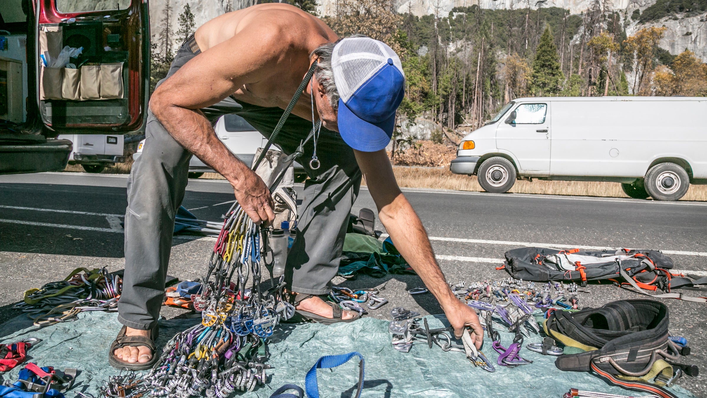 A shirtless climber sorts gear prior to a climb of El Capitan