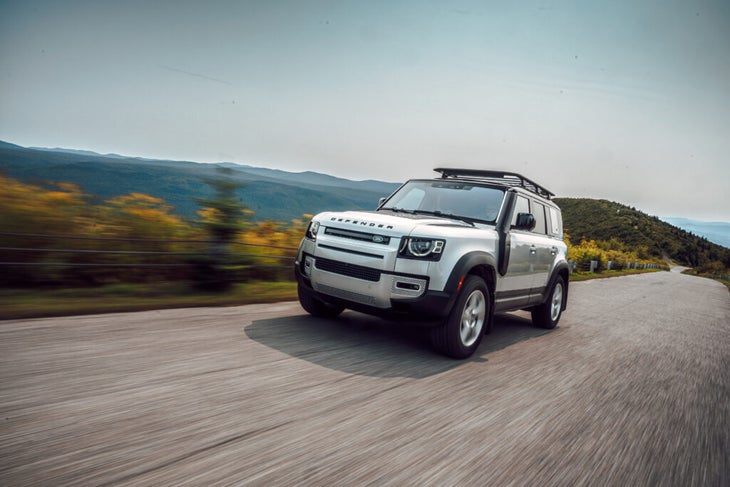 A Land Rover Defender driving in fall.