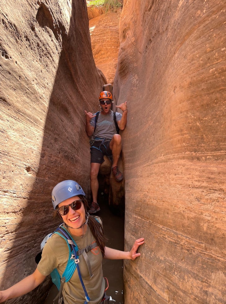 Two people climbing through a stone canyon