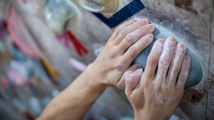 Hands gripping hold on climbing wall