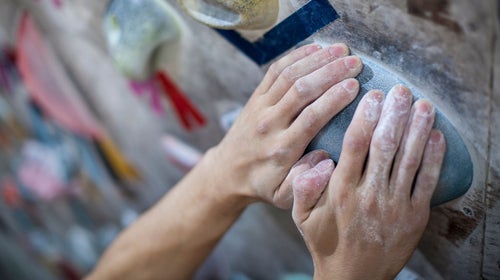 Hands gripping hold on climbing wall