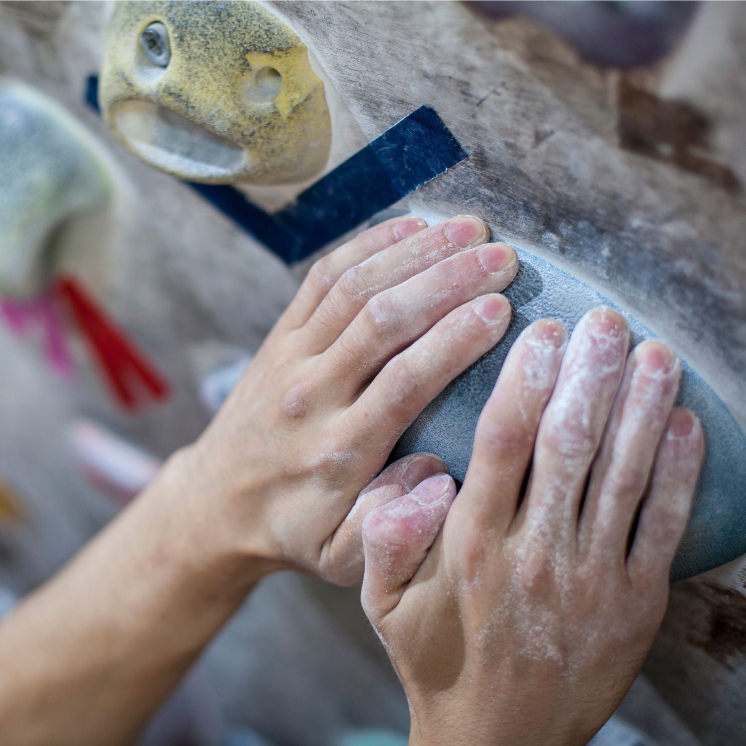 Hands gripping hold on climbing wall