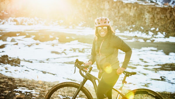 Portrait of smiling female cyclist riding gravel bike at sunset on winter evening