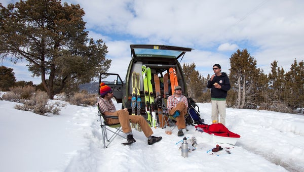 Skiers hanging out behind a van