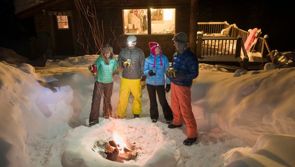 A group of adults enjoying an evening fire built in a snowpit outside of a backcountry ski hut near Molas Pass, Silverton, Colorado.