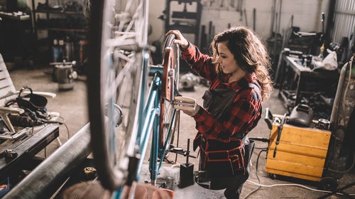 Woman repairing bicycle in workshop