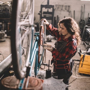 Woman repairing bicycle in workshop