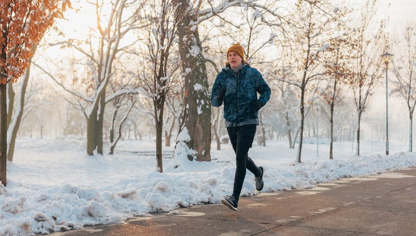 man running by the river on a beautiful snowy winter day