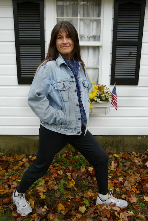 Elite runner poses in a jacket, in front of a white house