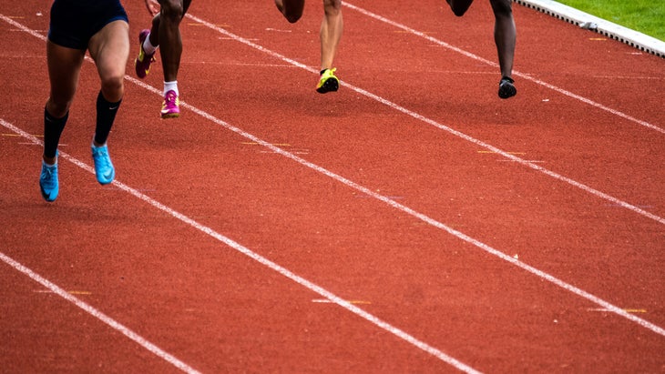 four people running on a track, just their legs and feet