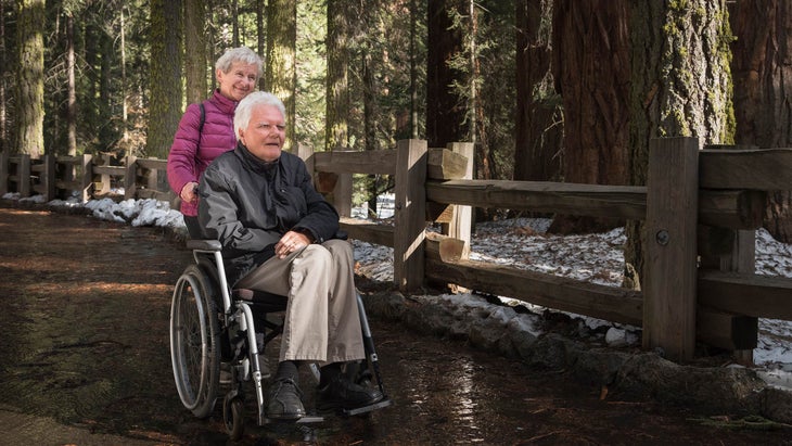 woman pushes man wheelchair sequoias