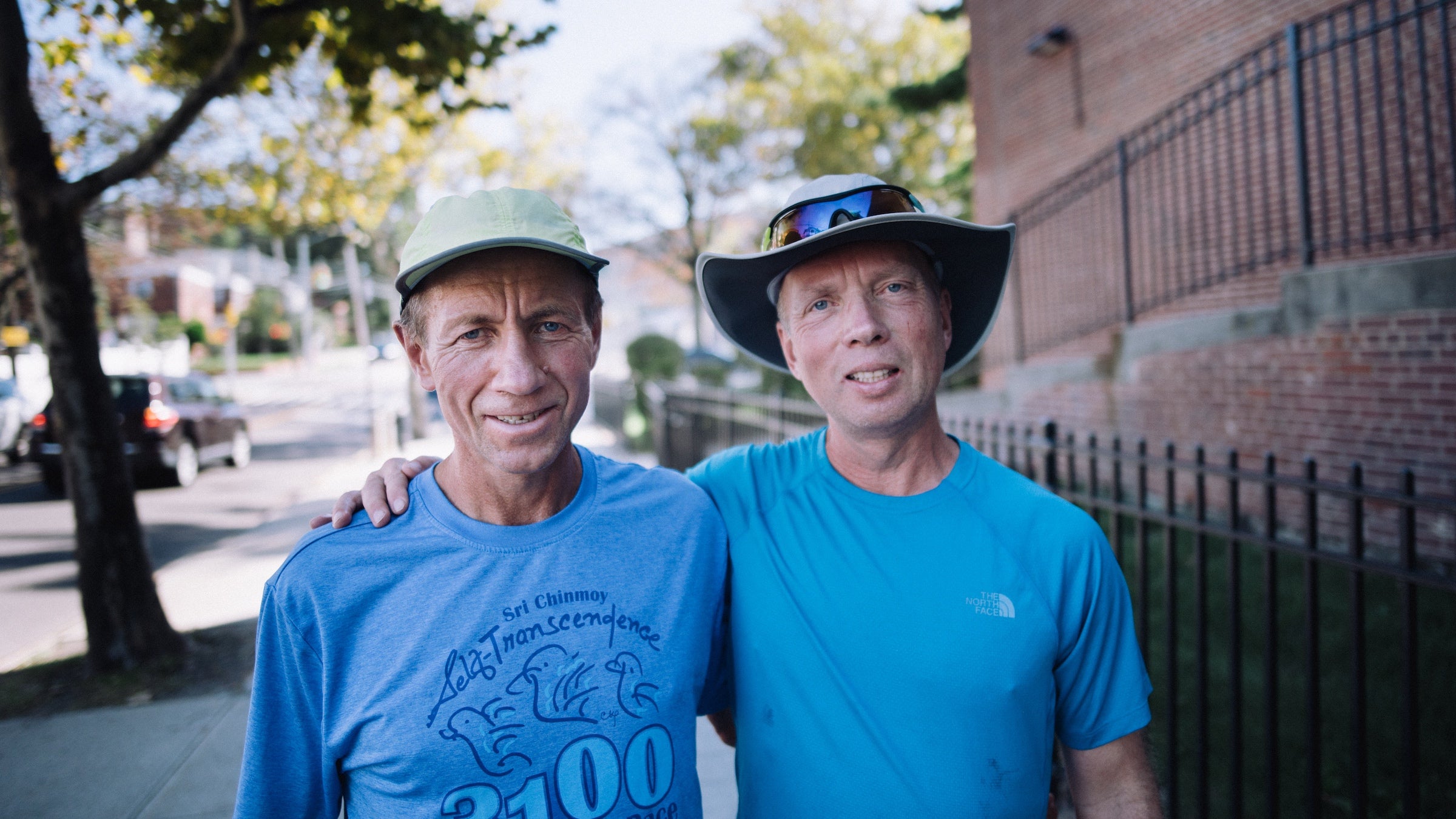Two runners in blue shirts have arms around each other at the race