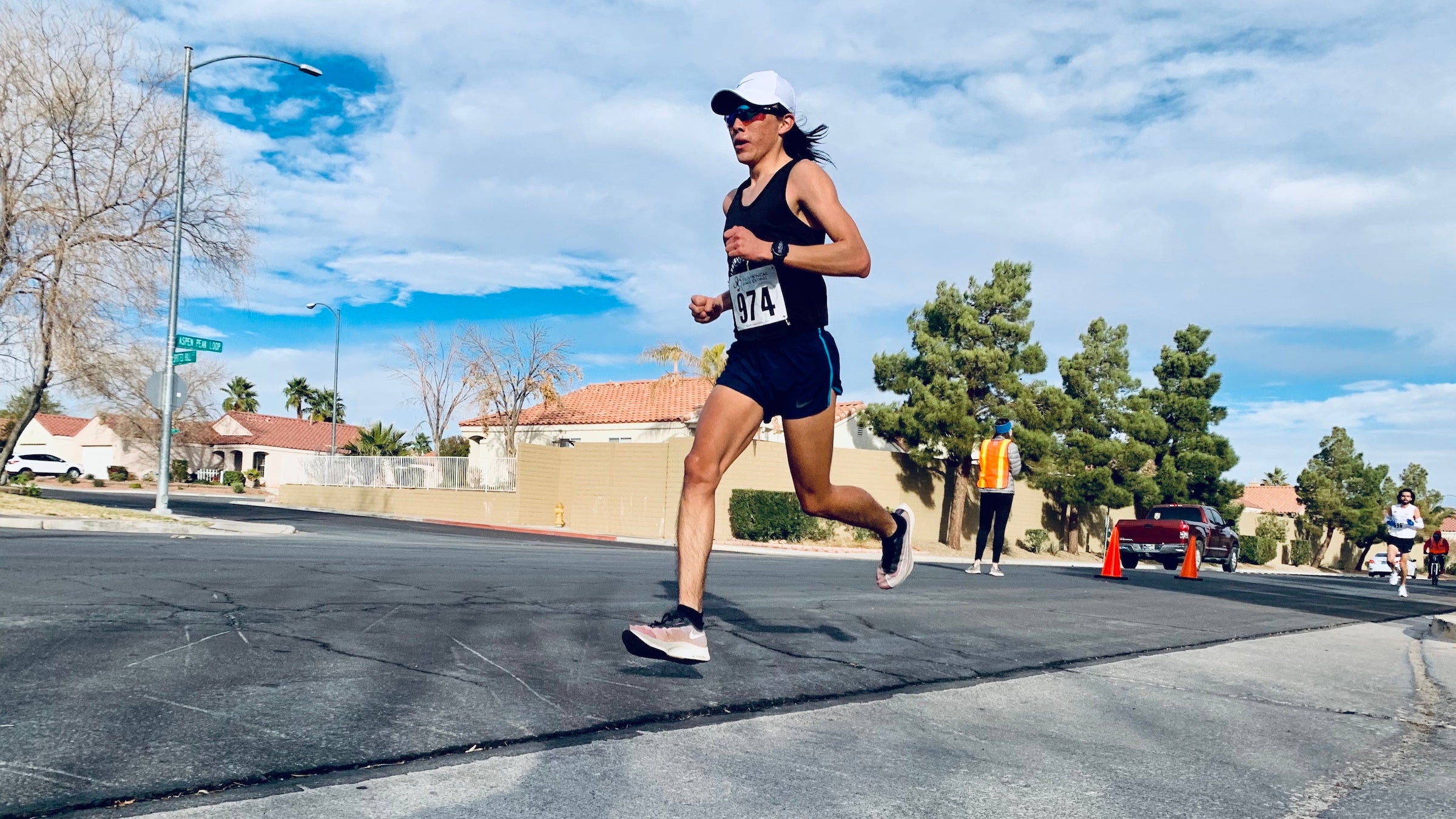 Indigenous runner on pavement with blue sky and wearing black