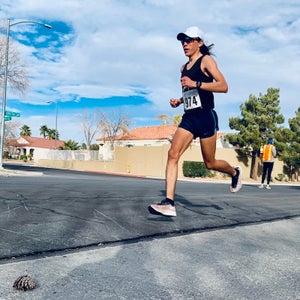 Indigenous runner on pavement with blue sky and wearing black