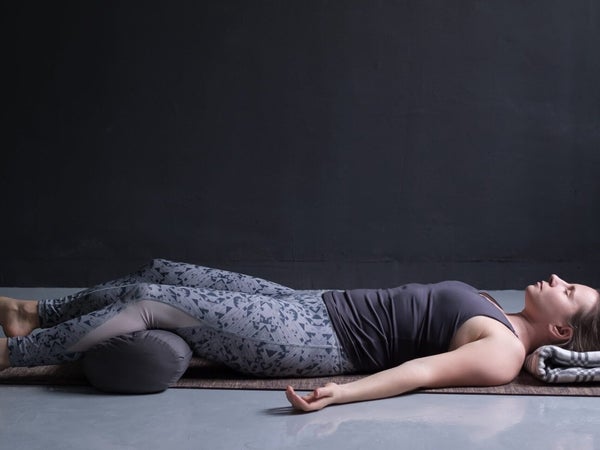 Woman lying on her back in Savasana to help her sleep better