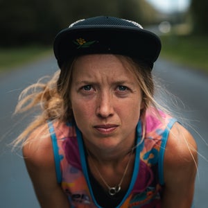 a female runner with a hat on wears pink singlet and looks into the camera