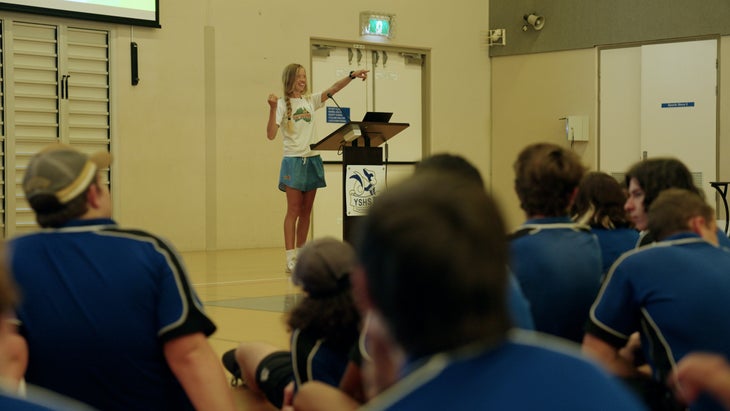 a women delivers a presentation in a gymnasium to students