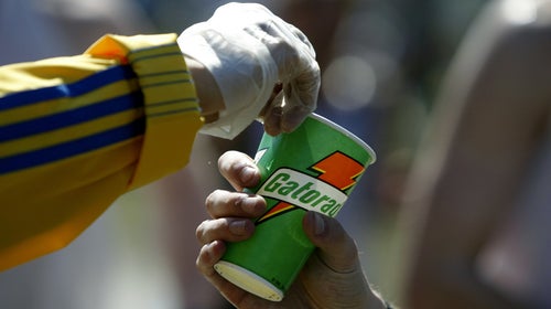 A detail shot of a volunteer as he hads a Gatorade refreshment cup to a runner as he passes through a water station in the town of Natick during the Boston marathon