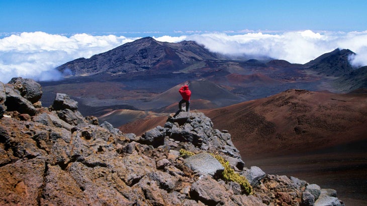 A man snaps a picture from a rocky perch atop Maui鈥檚 Haleakala crater.