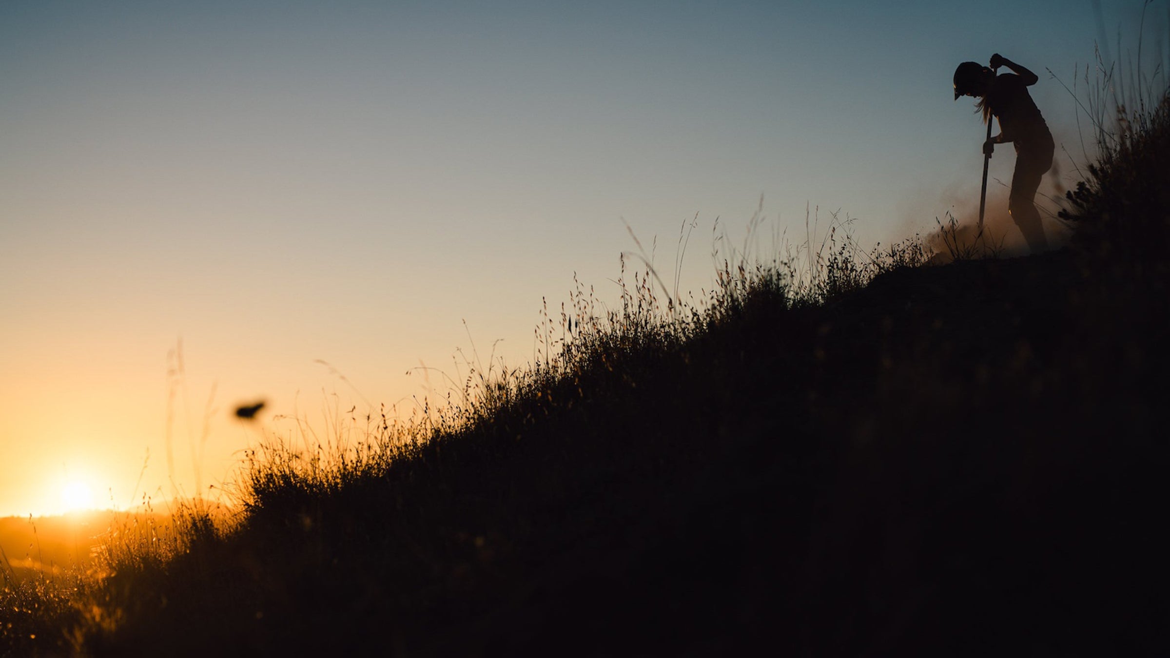 Silhouette of person digging trail