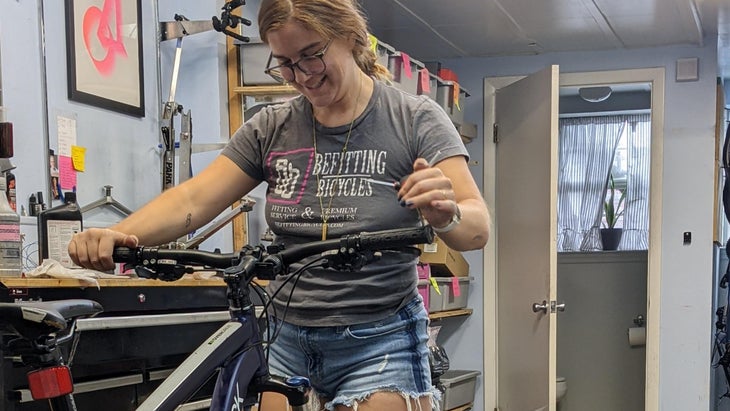 Woman in gray t-shirt working on a bicycle in a shop