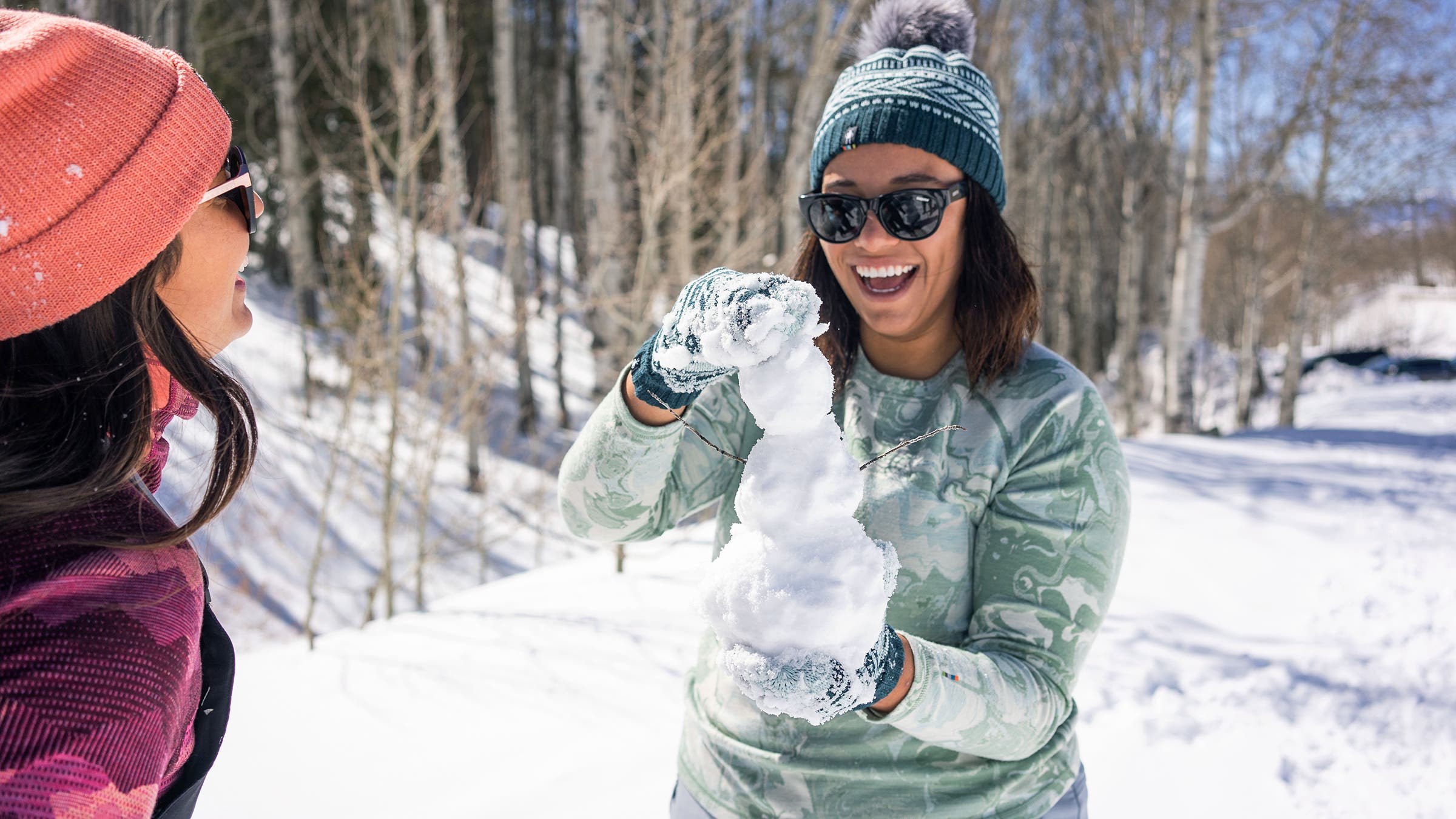 Person playing with snow wears Smartwool Thermal Baselayer Plus