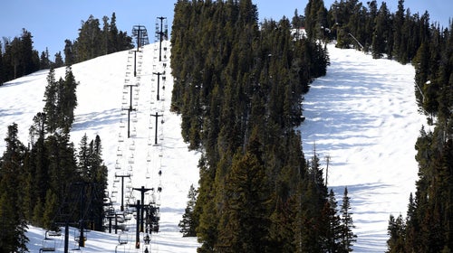 People ride a chair lift at a ski resort on a sunny day.