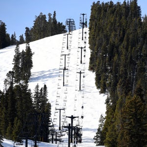 People ride a chair lift at a ski resort on a sunny day.