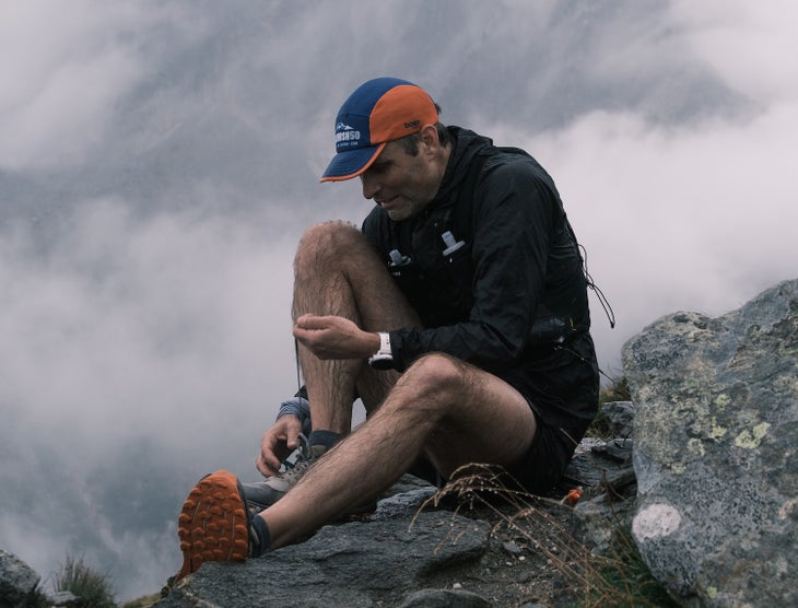 Ben Gibbard ties his shoelace on top of a mountain, grey fog in the background