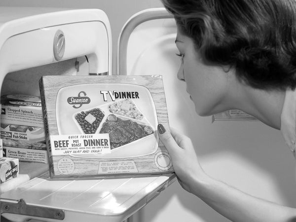 Vintage black and white photo of a woman looking at a TV dinner box