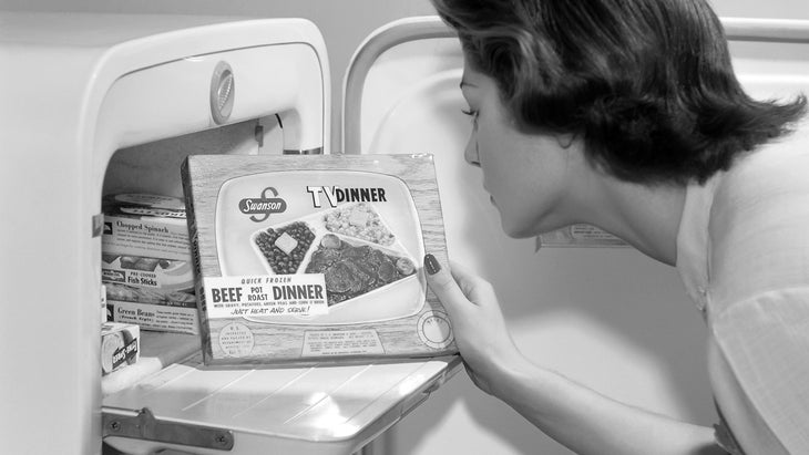Vintage black and white photo of a woman looking at a TV dinner box
