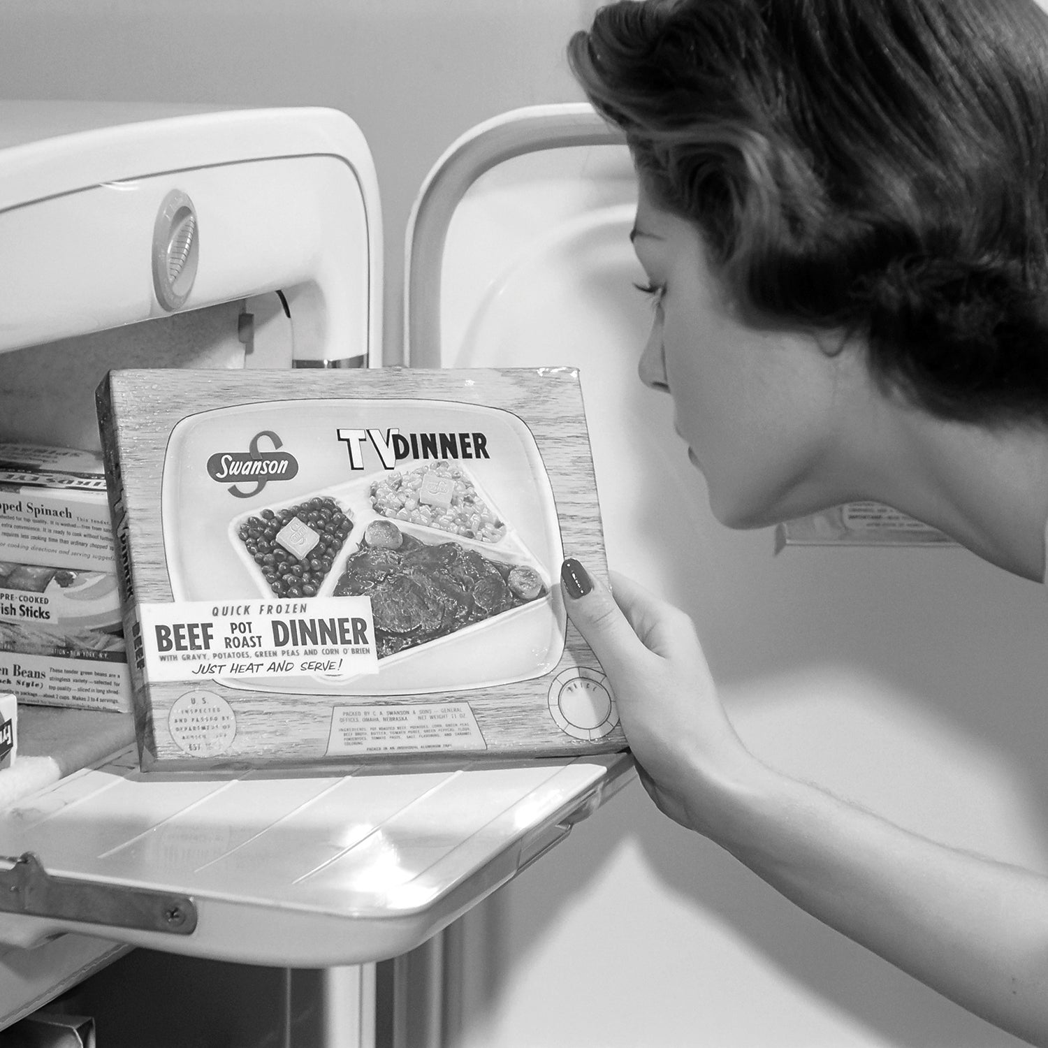 Vintage black and white photo of a woman looking at a TV dinner box