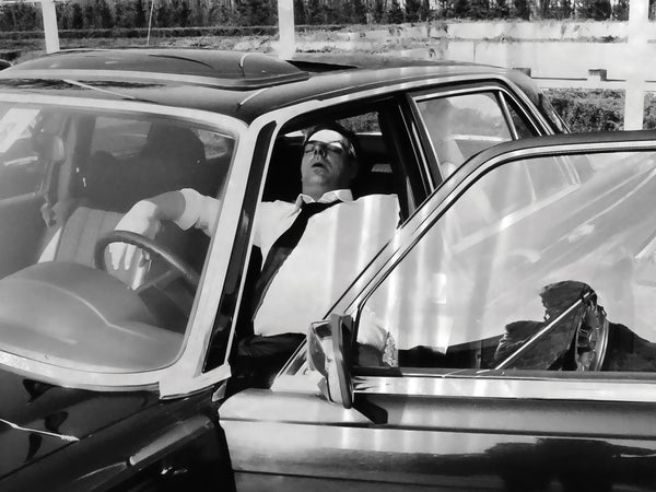 Vintage black and white photo of a man sleeping in a car