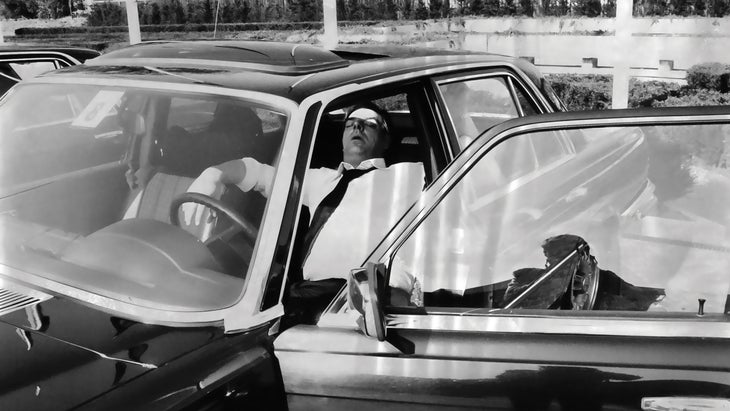 Vintage black and white photo of a man sleeping in a car