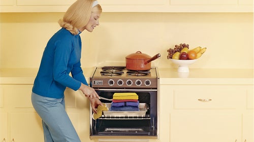 Vintage image of a woman pulling stacked hoodies out of an oven