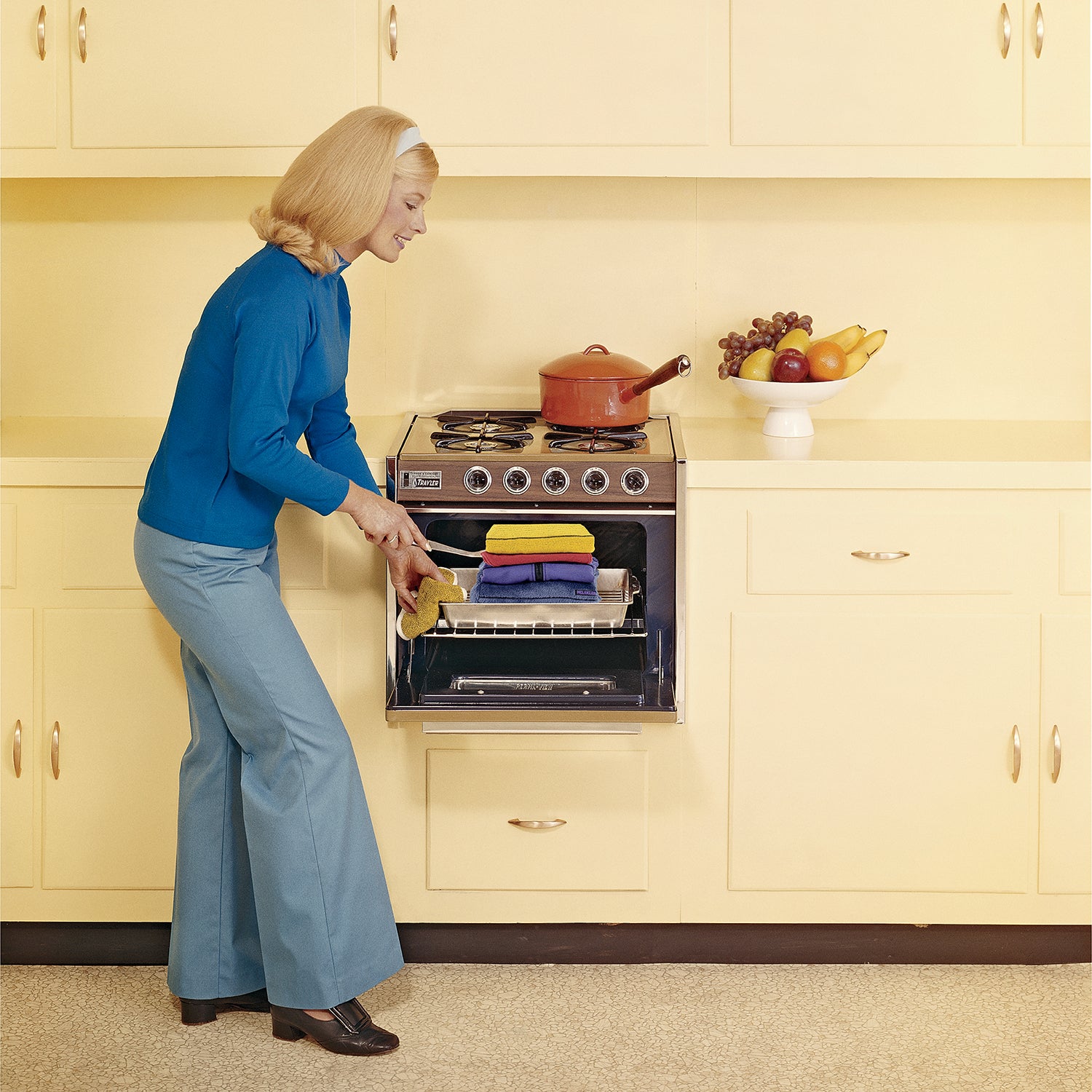 Vintage image of a woman pulling stacked hoodies out of an oven