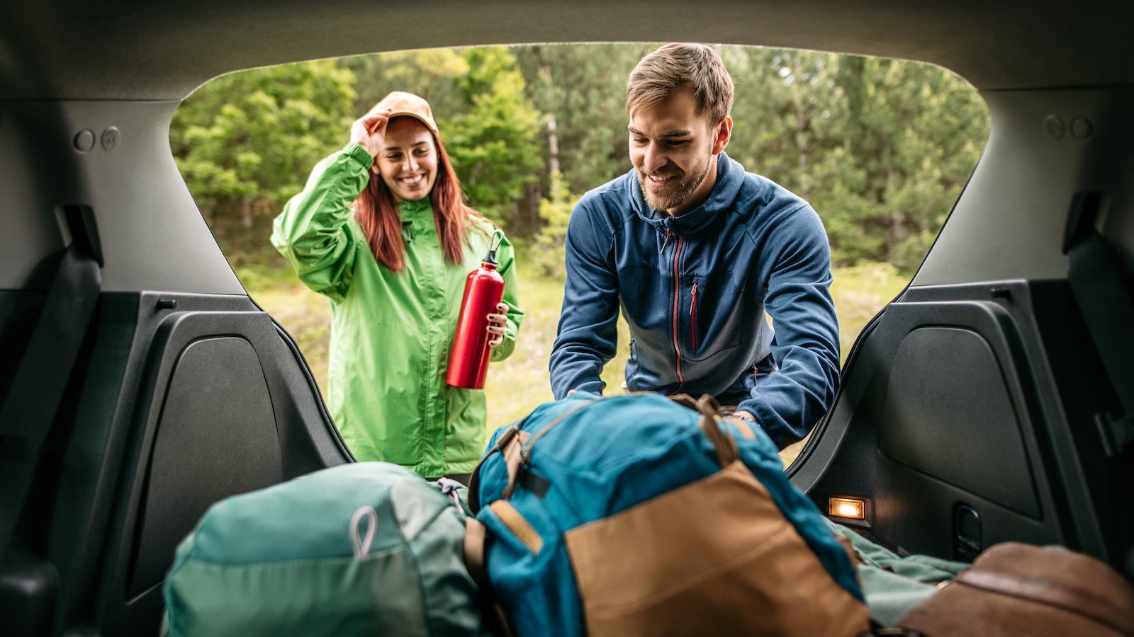 packing up camping equipment in the trunk of a car, ready for hiking