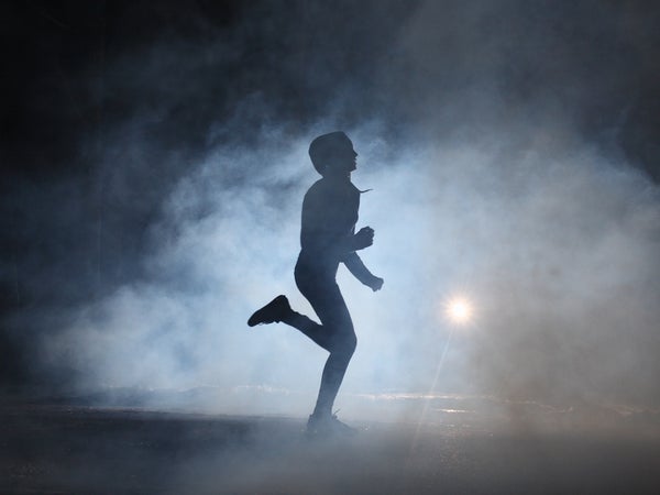 A hooded runner trains at night.