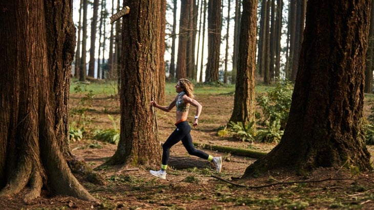 A runner runs through trees with black pants on.