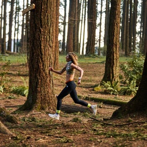 A runner runs through trees with black pants on.