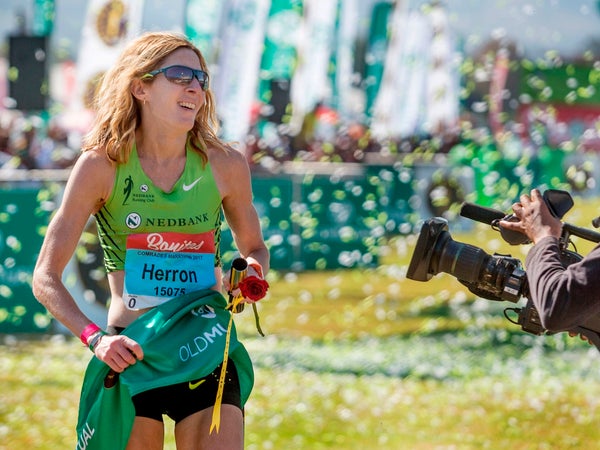Camille Herron is crossing the finish line, dressed in green, with confetti everywhere.