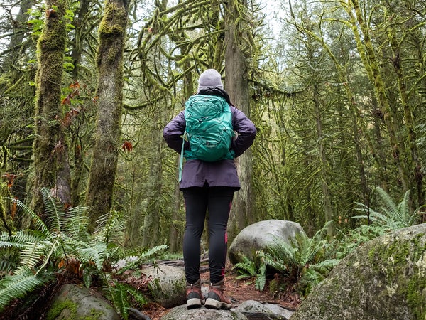 Forest Bathing - trees covered in moss and lichen surround a Eurasian woman in Lynn Canyon Park, North Vancouver, British Columbia, Canada