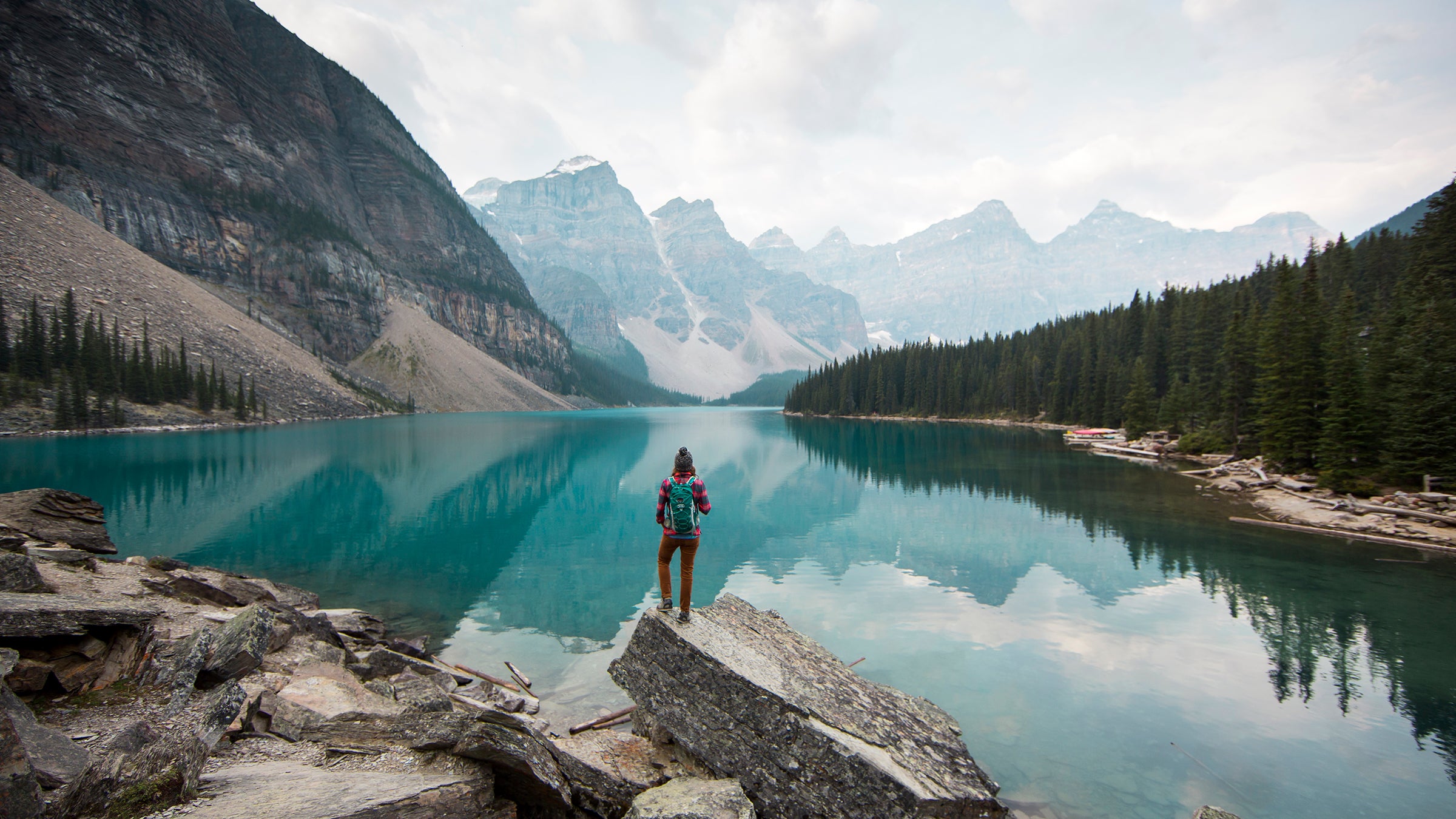 A woman standing on a scenic lookout overlooking Moraine Lake in Alberta, Canada.