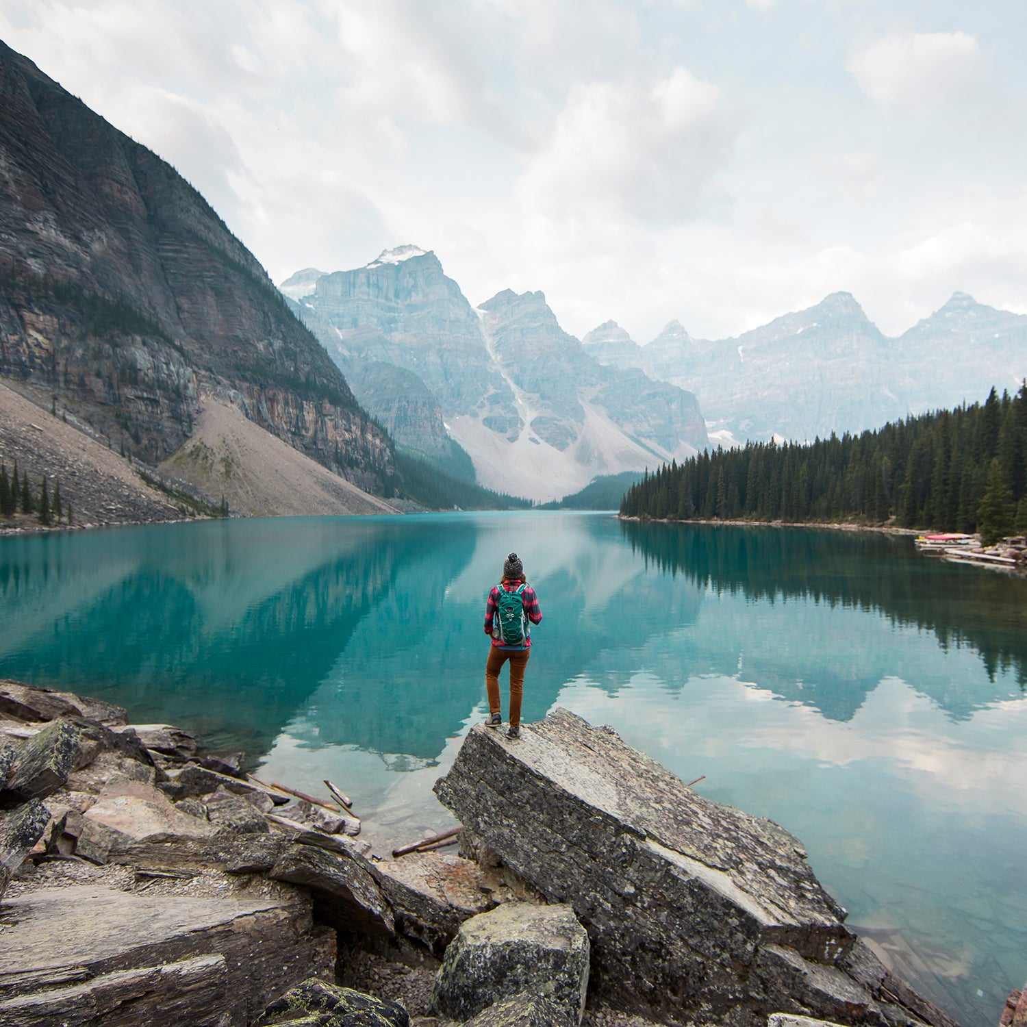 A woman standing on a scenic lookout overlooking Moraine Lake in Alberta, Canada.