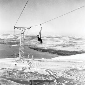 Black and white image of a single person alone on a chairlift
